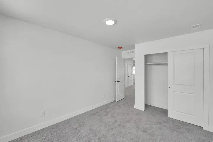 Neutral wall color, grey carpeting, recessed ceiling light, white baseboards, and a sliding closet door