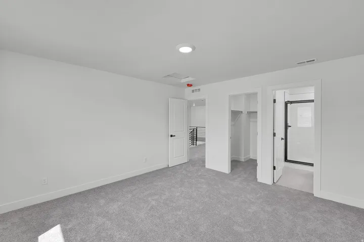 Spacious room featuring light gray carpet flooring, white walls, and a recessed ceiling light