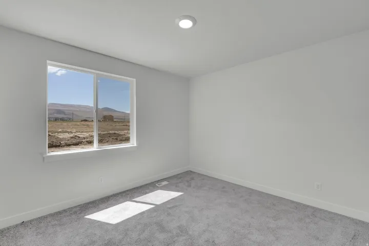 Bright room featuring a large window, recessed ceiling light, white walls, gray carpeting, and white baseboards