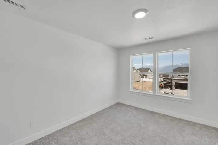 Bright room featuring two large windows, light gray carpeting, white walls, white baseboards, and an overhead flush-mount light fixture