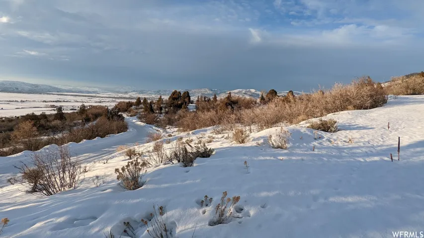 Expansive snow-covered terrain featuring a distant valley and mountain ranges