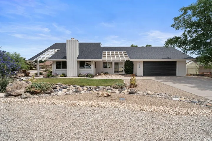 Single-story residence featuring a dark asphalt shingle roof, white exterior, and a two-car garage with a dark door