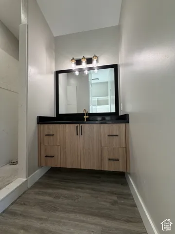 Floating wood-finish vanity with ample storage, black countertop, and gold-finish faucet