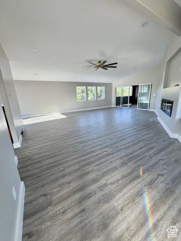 Primary Bedroom Vaulted ceiling with recessed lighting, wood-finish flooring, ceiling fan, triple windows, and built-in fireplace