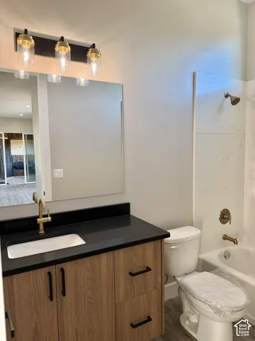 Wood-finish vanity with a rectangular undermount sink, dark countertop, and gold-tone faucet