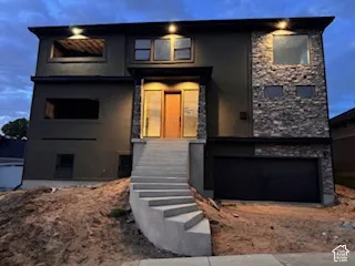 Contemporary facade featuring dark stucco and natural stone accents