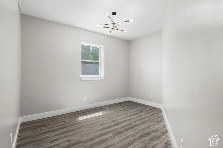 Room featuring wood-finish flooring, a modern chandelier with multiple exposed bulbs, and a window with white trim