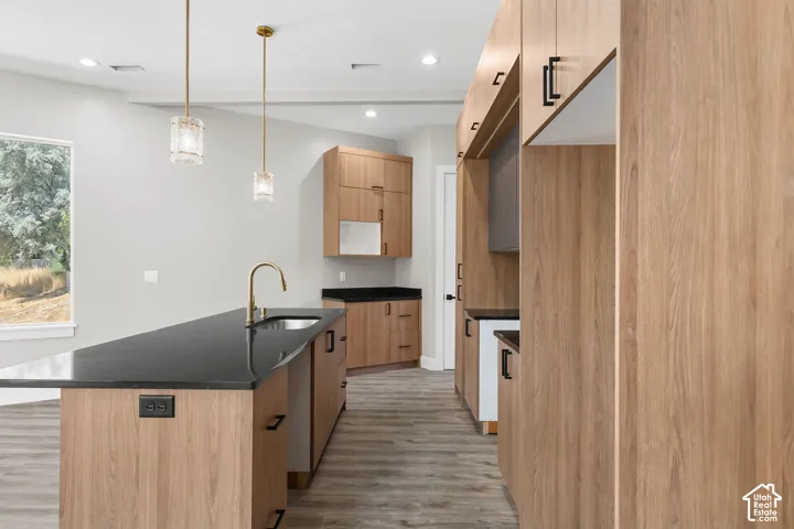 Kitchen featuring a dark countertop island with an undermount sink and gold-finish faucet