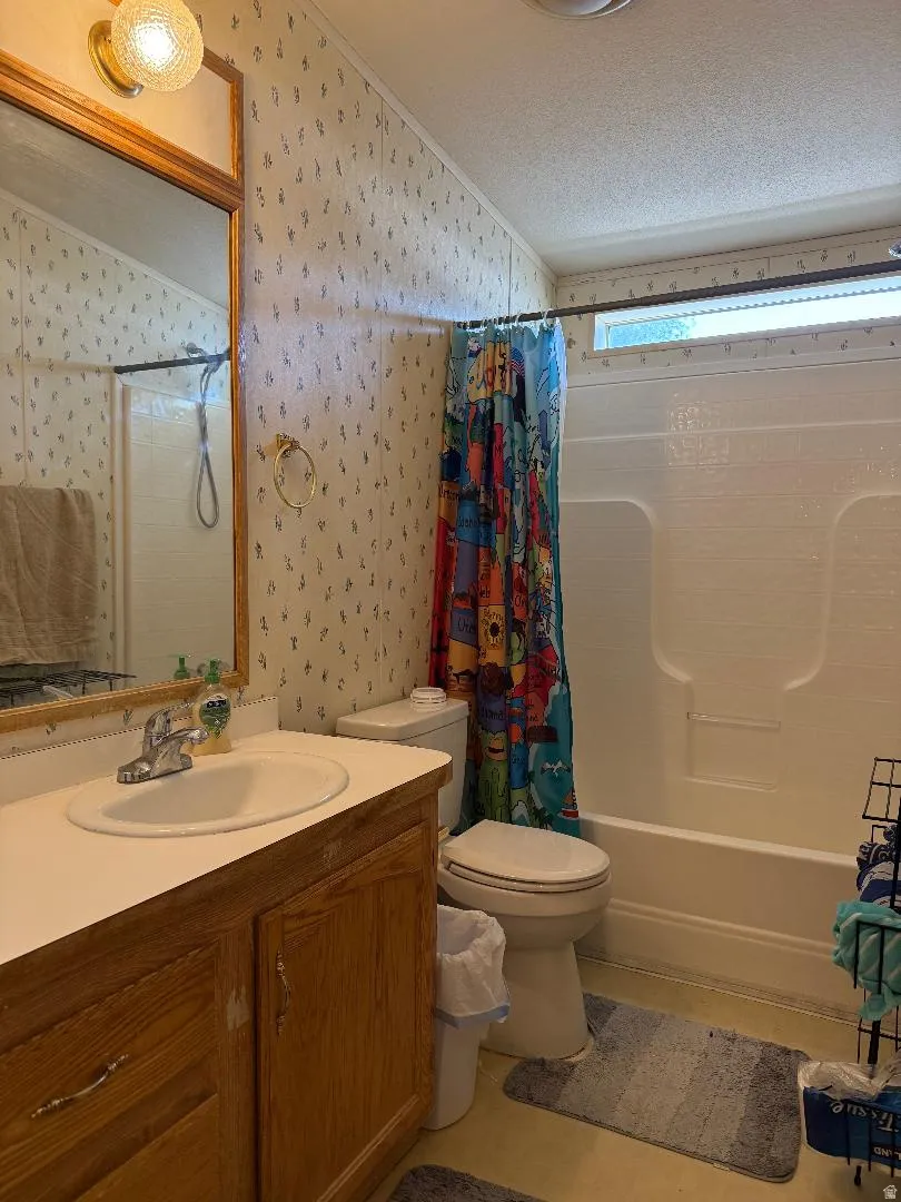 2nd Bathroom featuring a wood-finish vanity with an integrated sink, a white toilet, and a white bathtub with an overhead shower