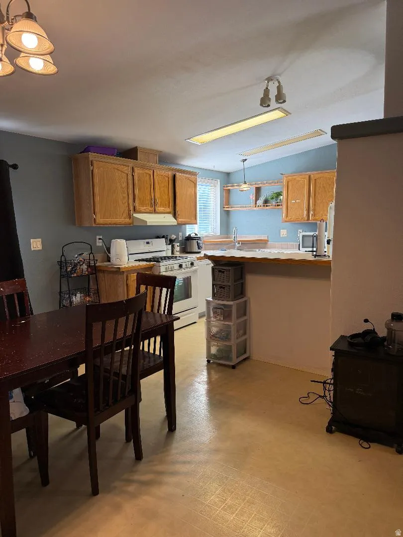 Kitchen featuring wood cabinetry, white appliances, a breakfast bar, and wood-finish flooring
