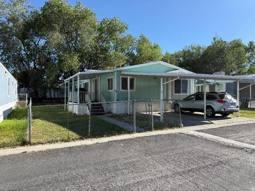 Single-story residence featuring a carport, front porch, and chain-link fencing