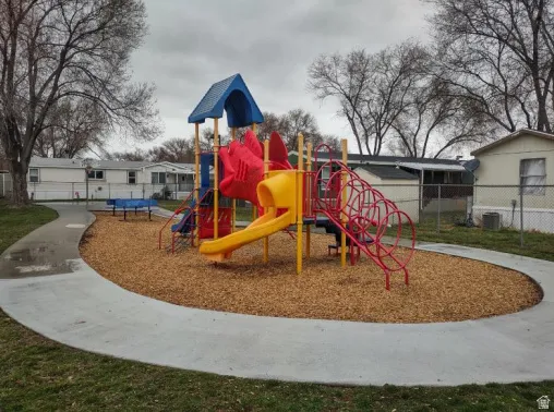 Recreational area featuring a colorful playground structure with slides and climbing elements set on a wood chip surface