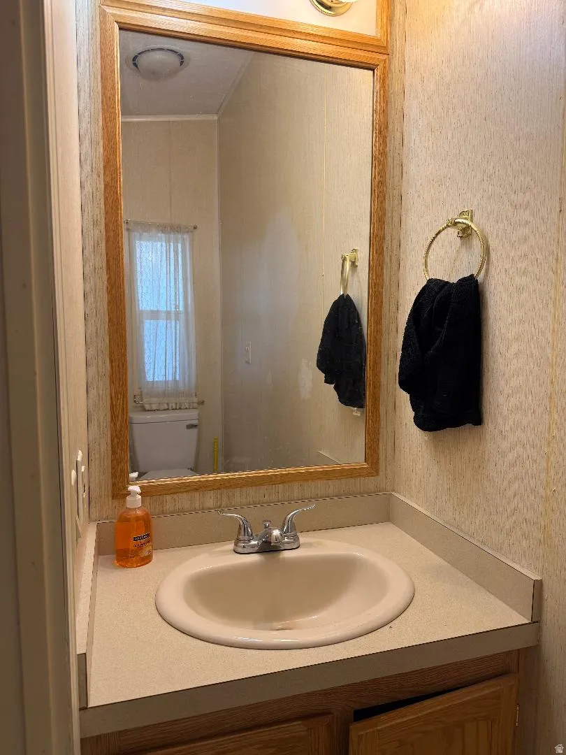 1/2 Bathroom vanity with a light wood-finish mirror, integrated sink, and light-toned countertop