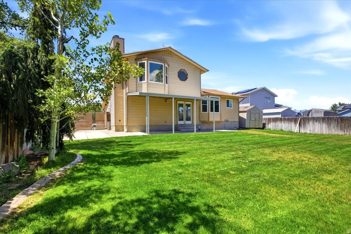 Expansive rear lawn featuring a covered patio, multiple windows, and a bay window on the upper level
