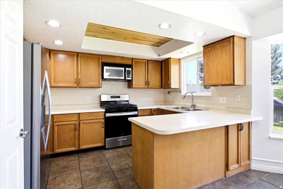 Kitchen featuring light wood cabinetry, white countertops, stainless steel appliances, and recessed lighting