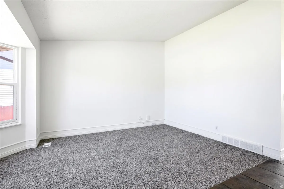 Spacious room featuring neutral white walls and plush gray carpeting