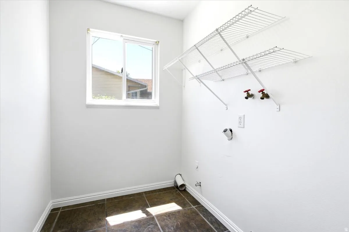 Laundry area featuring ceramic tile flooring, a window, white walls, and built-in wire shelving