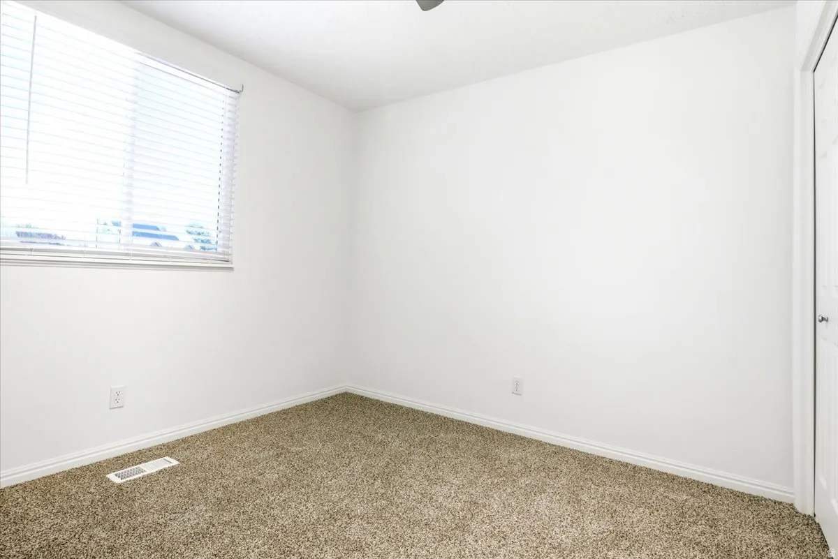 Bedroom featuring wall-to-wall carpeting, white walls, and a window with blinds