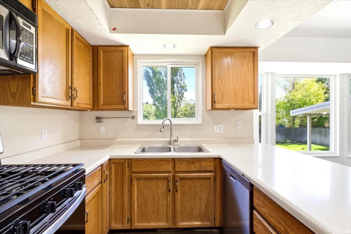 Kitchen featuring light wood cabinetry, light countertops, and a double basin stainless steel sink with a gooseneck faucet