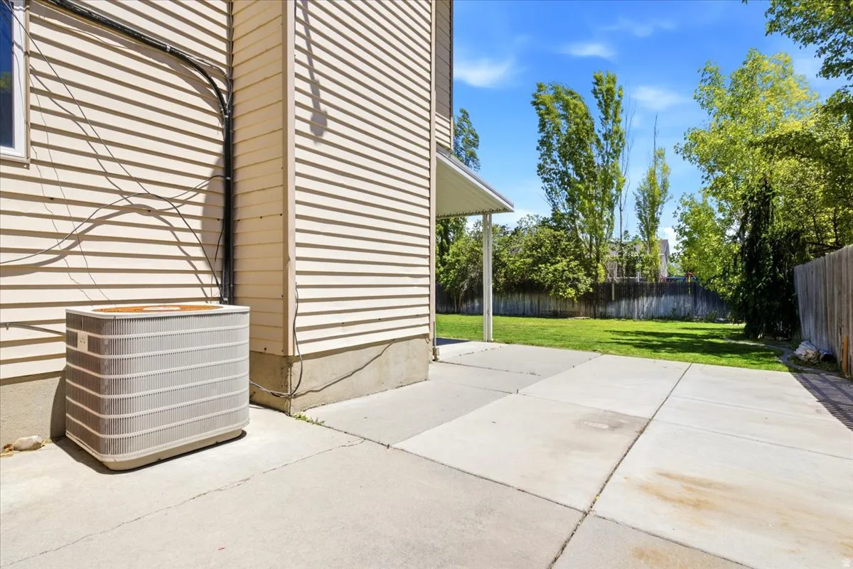 Exterior patio featuring concrete slab paving, a covered section, and a manicured lawn