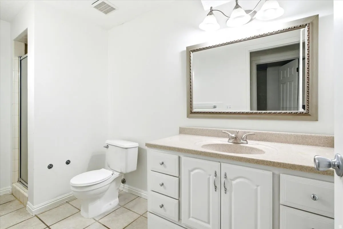 Bathroom featuring a white vanity with panel-front cabinetry, a light-colored countertop with an integrated sink, and a framed mirror