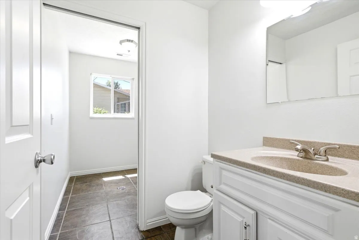 Bathroom vanity featuring a light-colored countertop with an integrated sink, brushed nickel faucet, and a large wall-mounted mirror