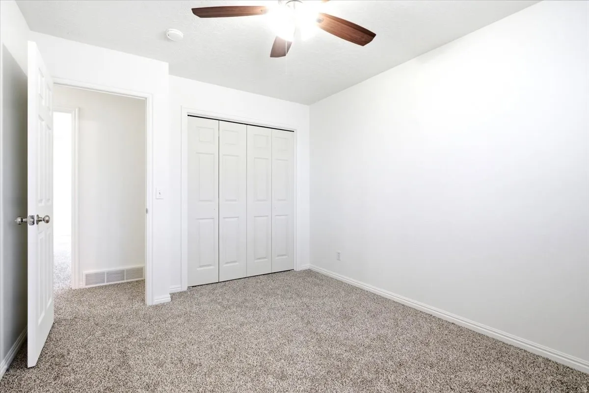Neutrally toned wall-to-wall carpeting complements the white walls and trim