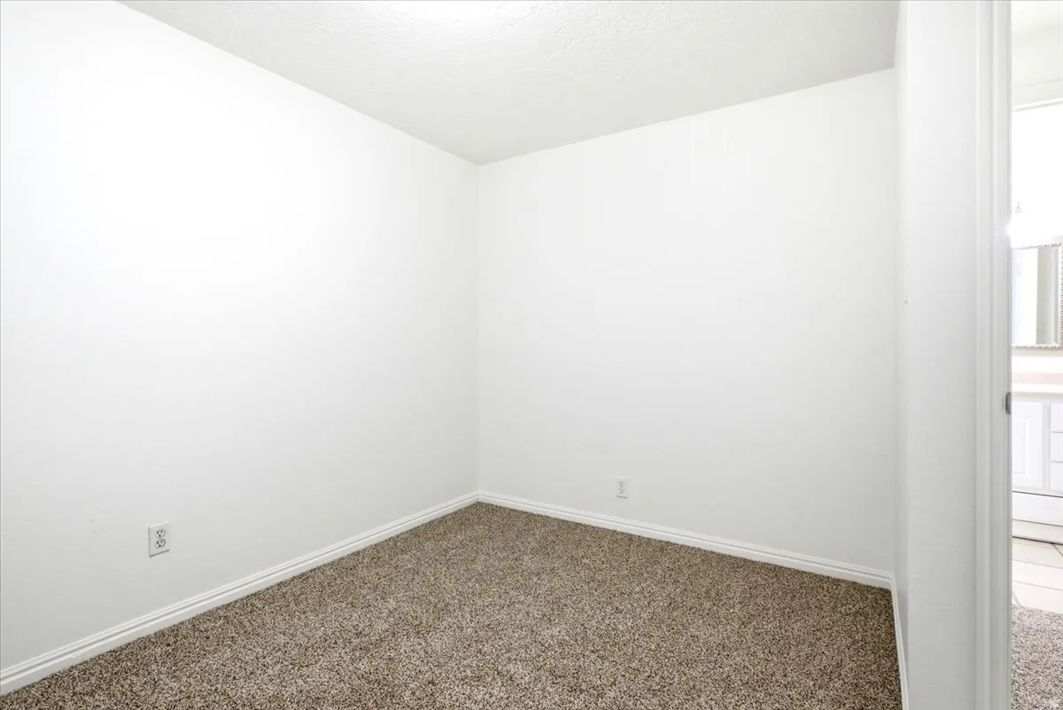 Room featuring neutral wall paint, textured ceiling, brown carpet flooring, and white baseboards