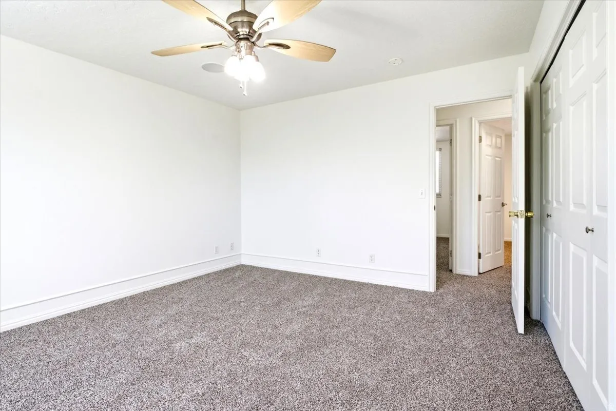 Spacious room with neutral gray carpeting, white walls, and white trim