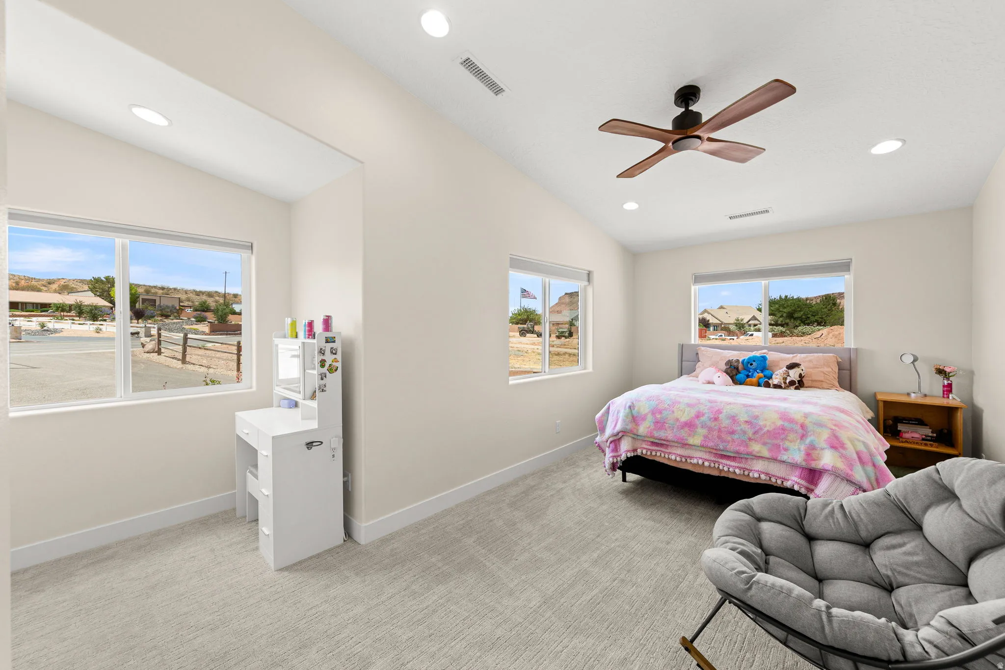 Spacious room featuring multiple windows, recessed lighting, vaulted ceilings, and a ceiling fan