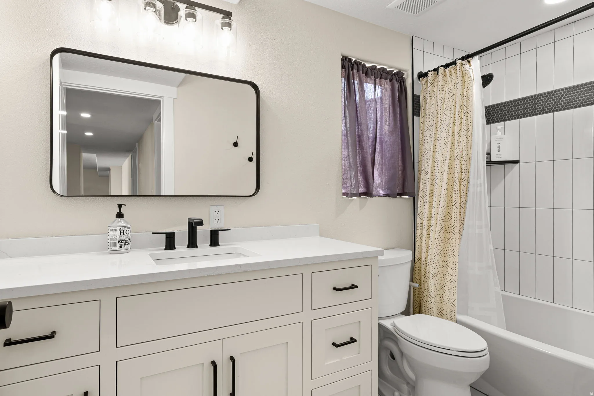 Bathroom featuring a white vanity with integrated sink, quartz countertop, and matte black hardware