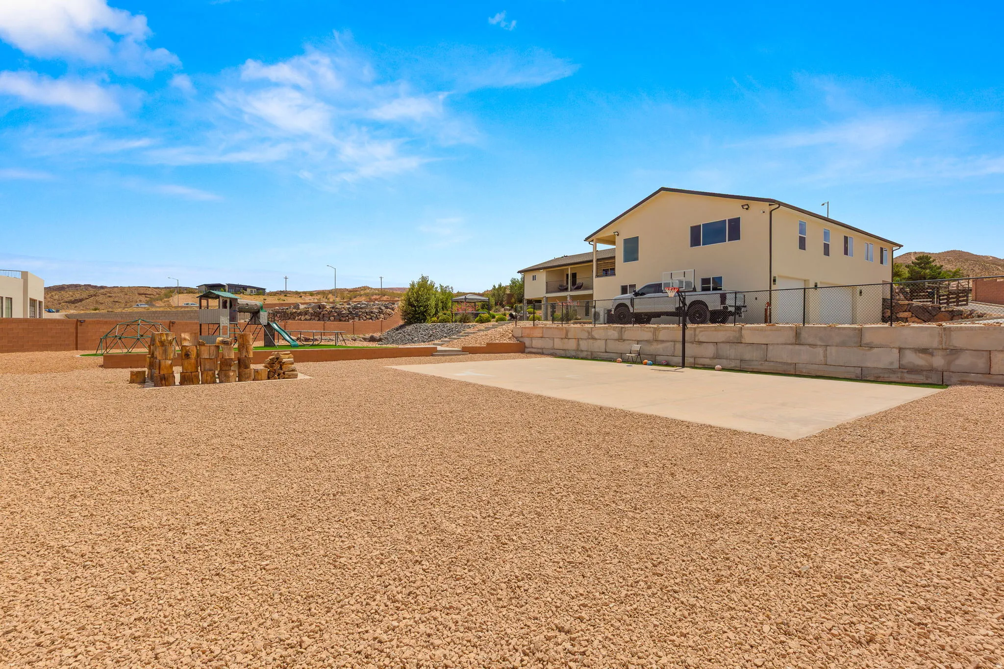 Expansive gravel yard featuring a concrete sports court and a dedicated play area with artificial turf