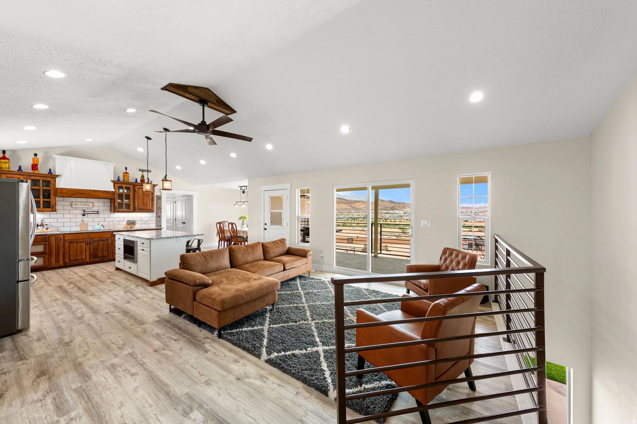 Open-concept living space featuring wood-finish flooring, a vaulted ceiling with recessed lighting, and a modern ceiling fan