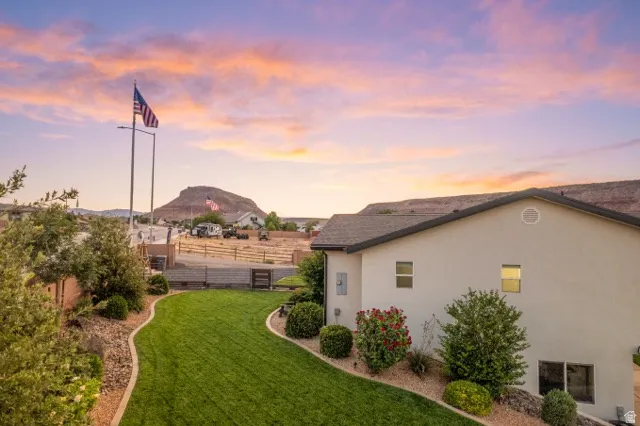 Expansive rear yard featuring a manicured lawn, established landscaping, and desert-inspired rock borders