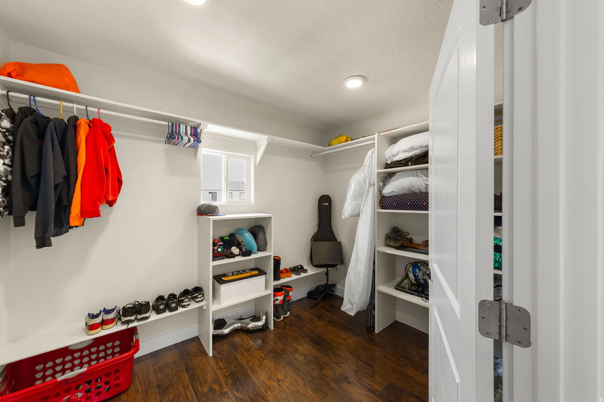 Walk-in closet featuring wood-finish flooring, recessed lighting, built-in shelving, hanging rod storage, and a white framed window