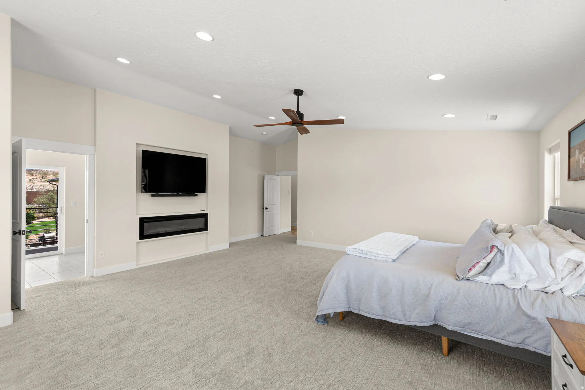 Spacious room featuring vaulted ceilings, recessed lighting, a built-in electric fireplace, and light-toned carpeting
