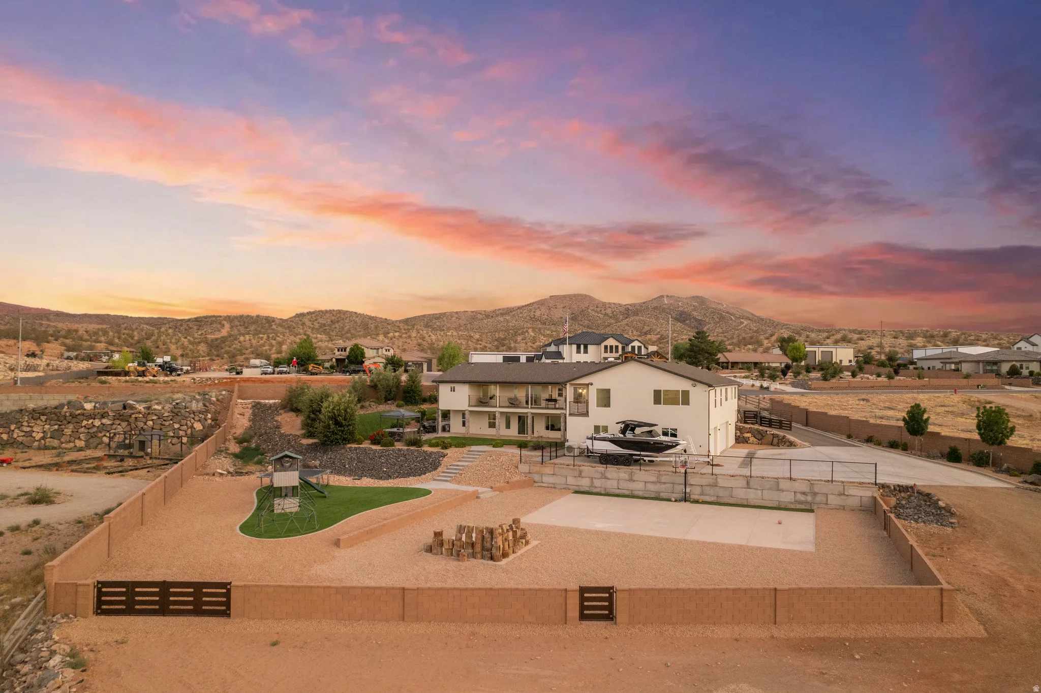 Spacious property featuring a multi-level home with balconies, extensive hardscaping, a large fenced yard, and a concrete patio