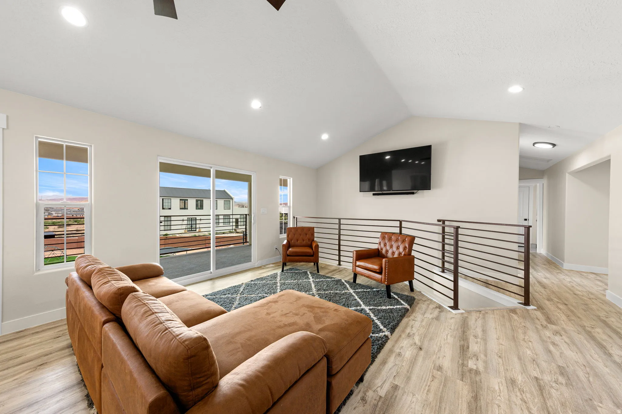Spacious open-concept room featuring vaulted ceilings, recessed lighting, and wood-finish flooring