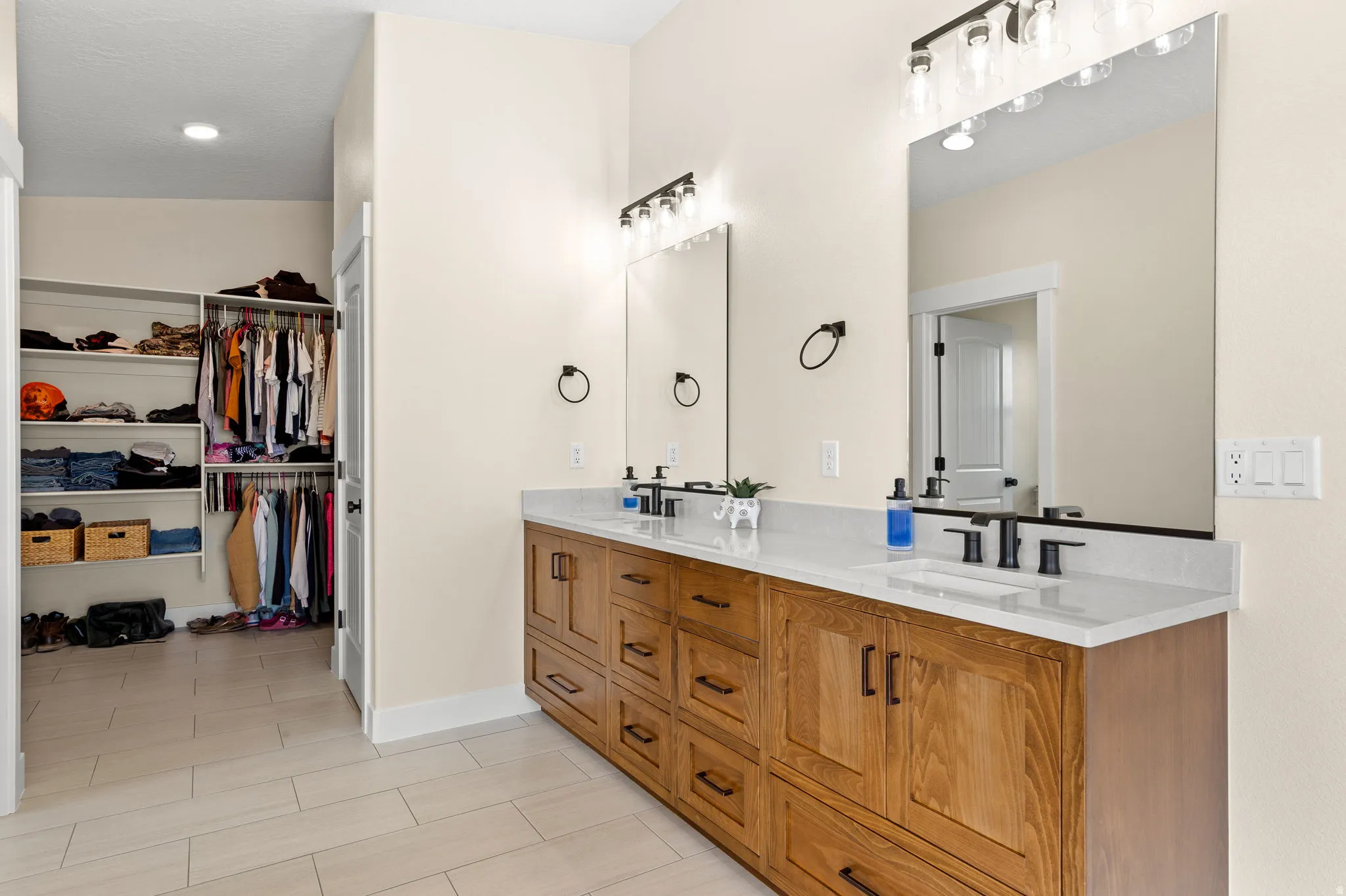 Dual vanity featuring wood cabinetry, white stone countertops, and matte black fixtures