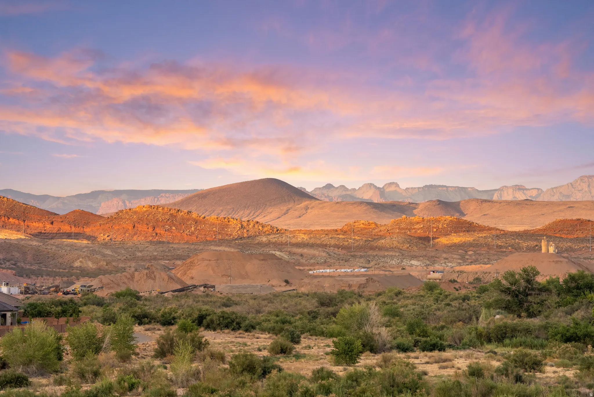 Expansive desert landscape featuring distant mountains and rolling hills under a vibrant sky