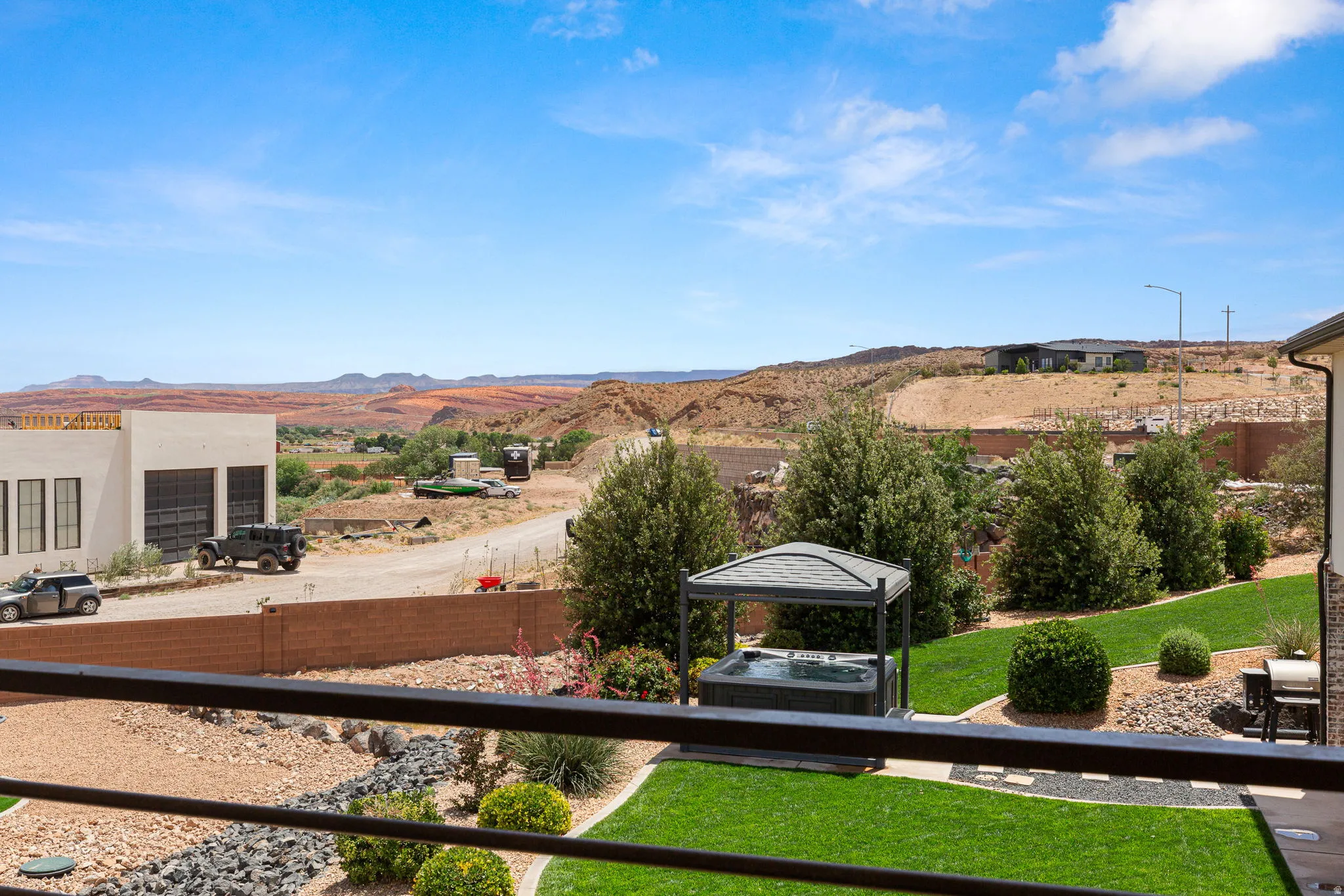 Expansive backyard featuring a manicured lawn, established landscaping, and a covered hot tub