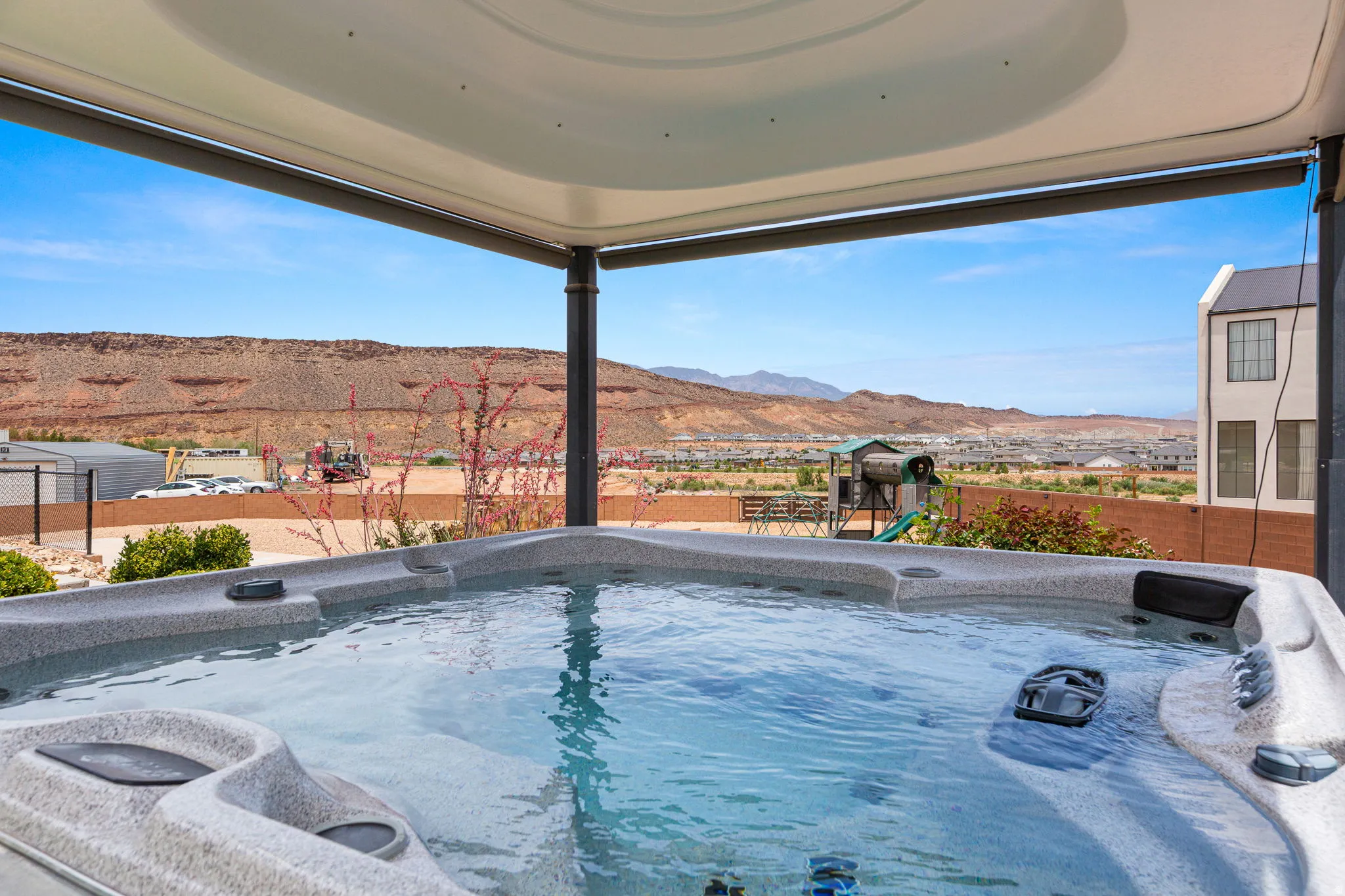 Outdoor spa under a covered patio, featuring a spacious basin and integrated seating