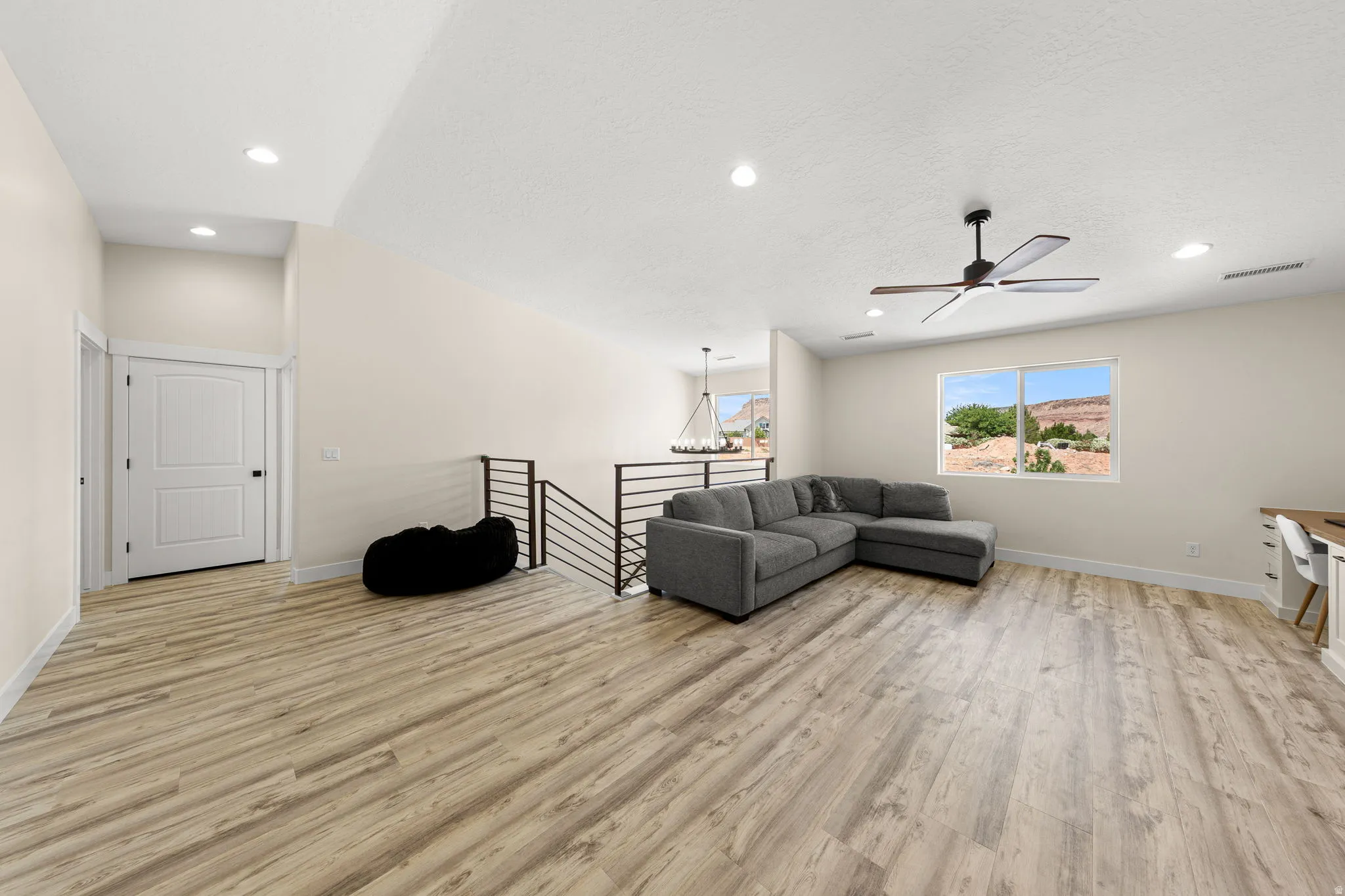 Spacious upper-level area featuring wood-finish flooring, a contemporary ceiling fan, recessed lighting, and a white interior door