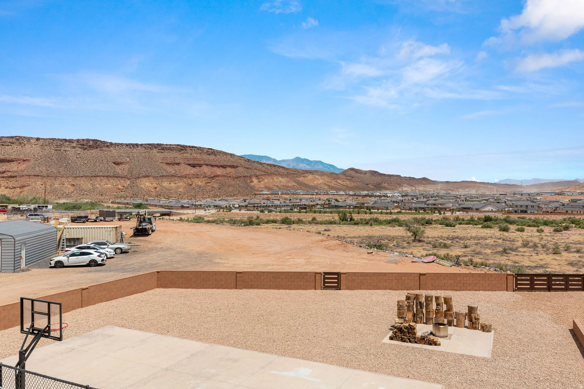 Expansive gravel yard with a concrete sport court and a built-in fire pit area