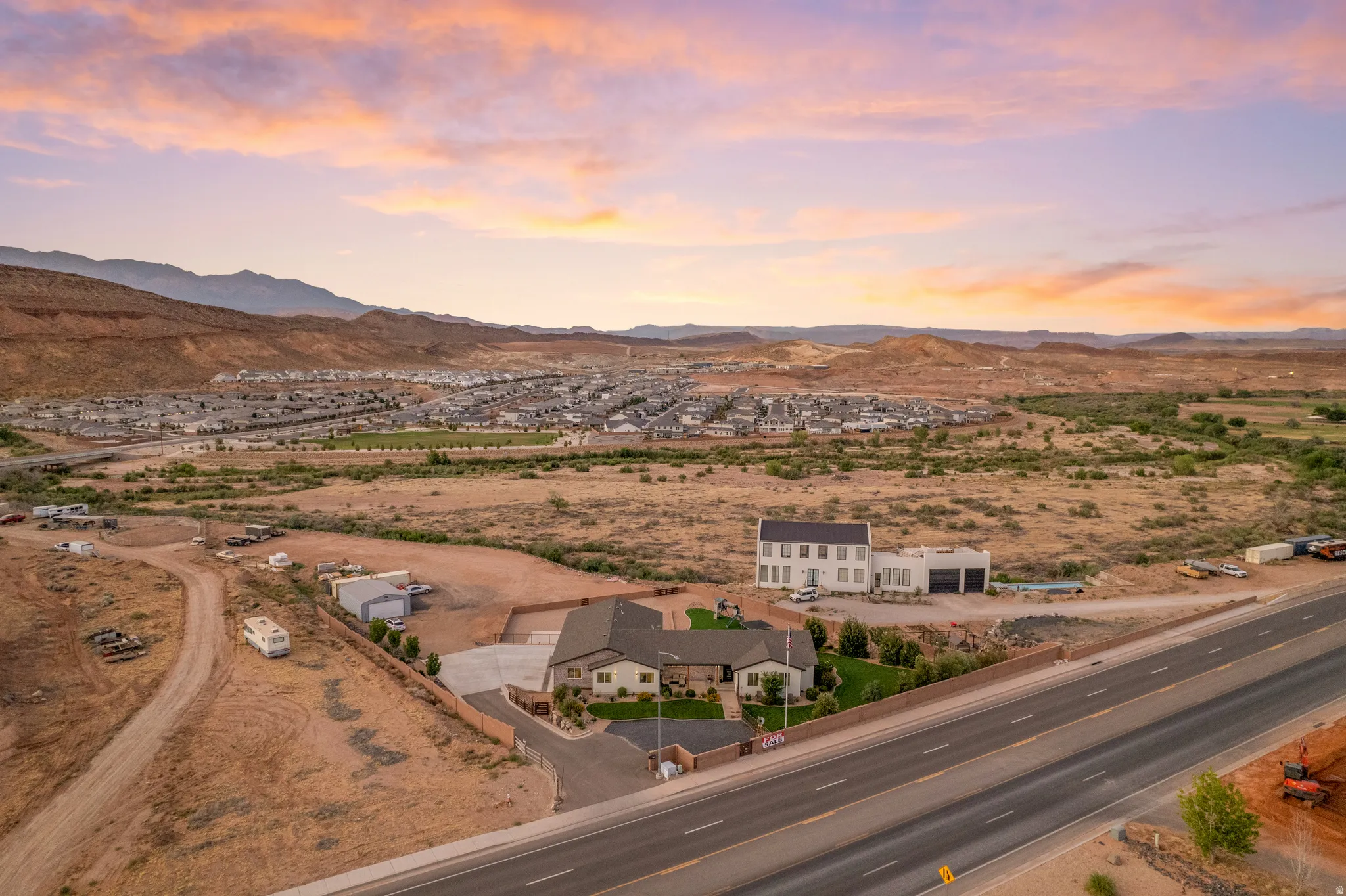 Expansive property featuring a modern two-story residence with a detached garage building, perimeter fencing, and established landscaping