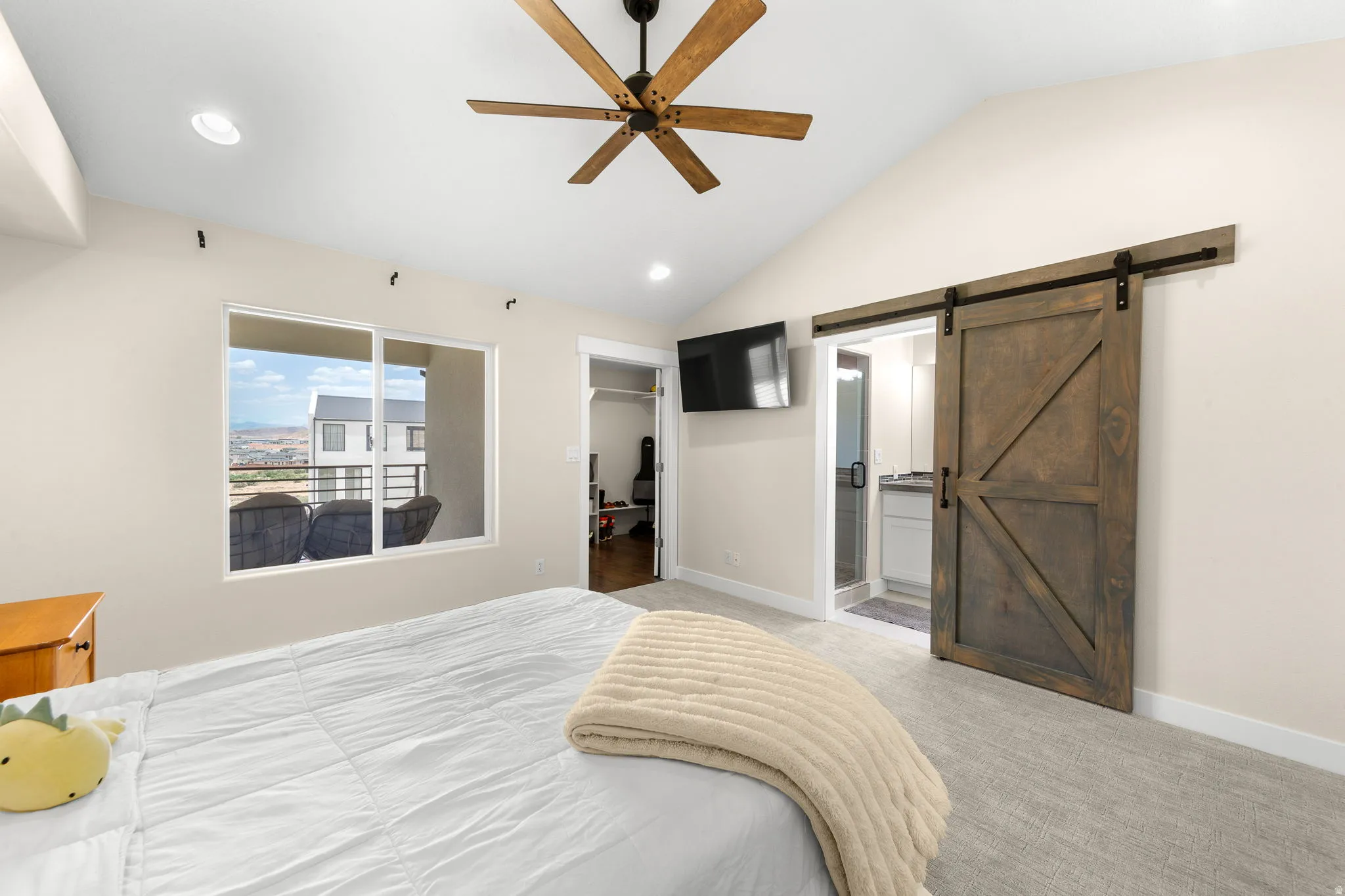 Vaulted ceiling with a wood-finish ceiling fan and recessed lighting