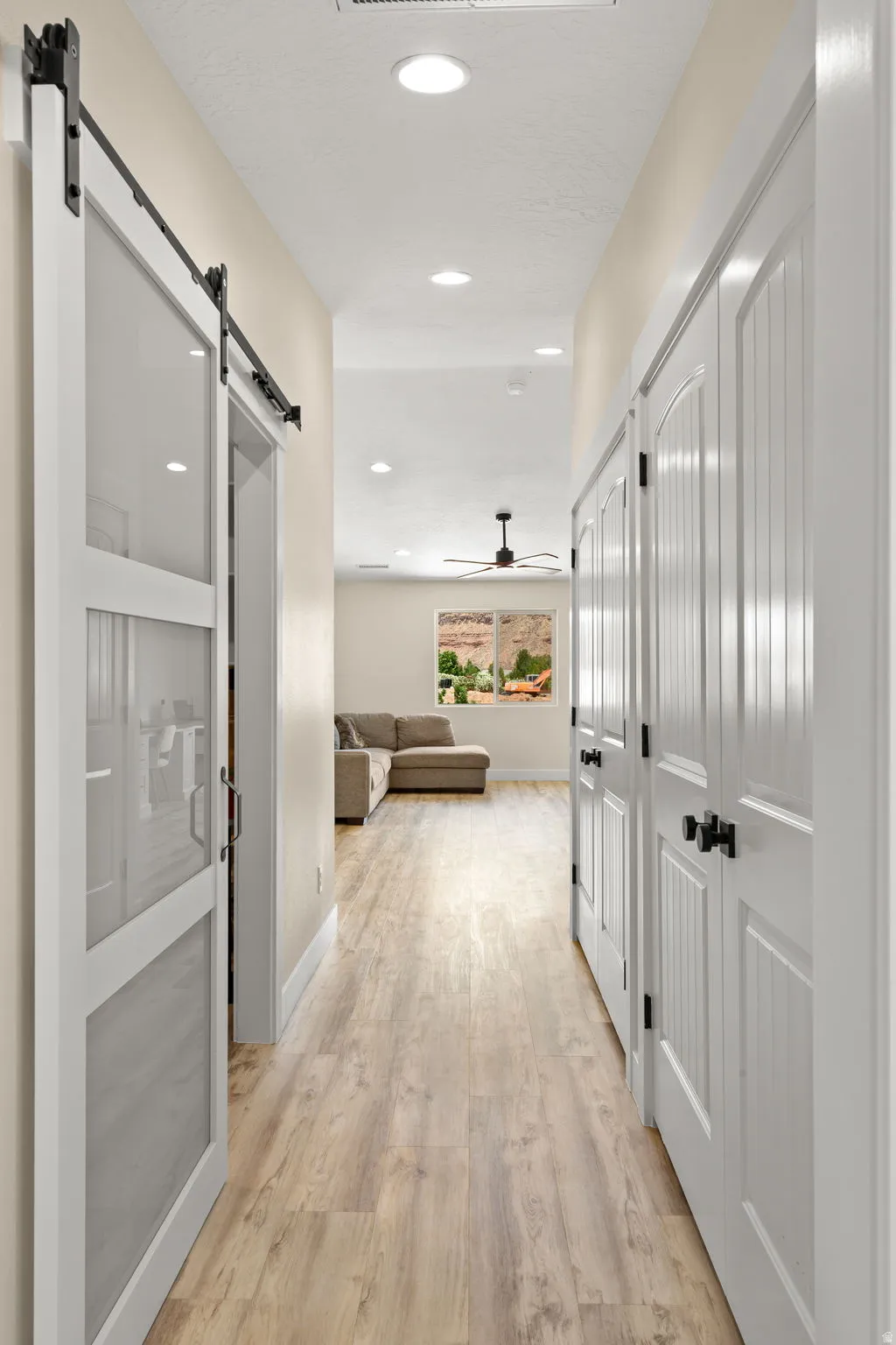 Hallway featuring wood-finish flooring, white paneled doors, and recessed lighting
