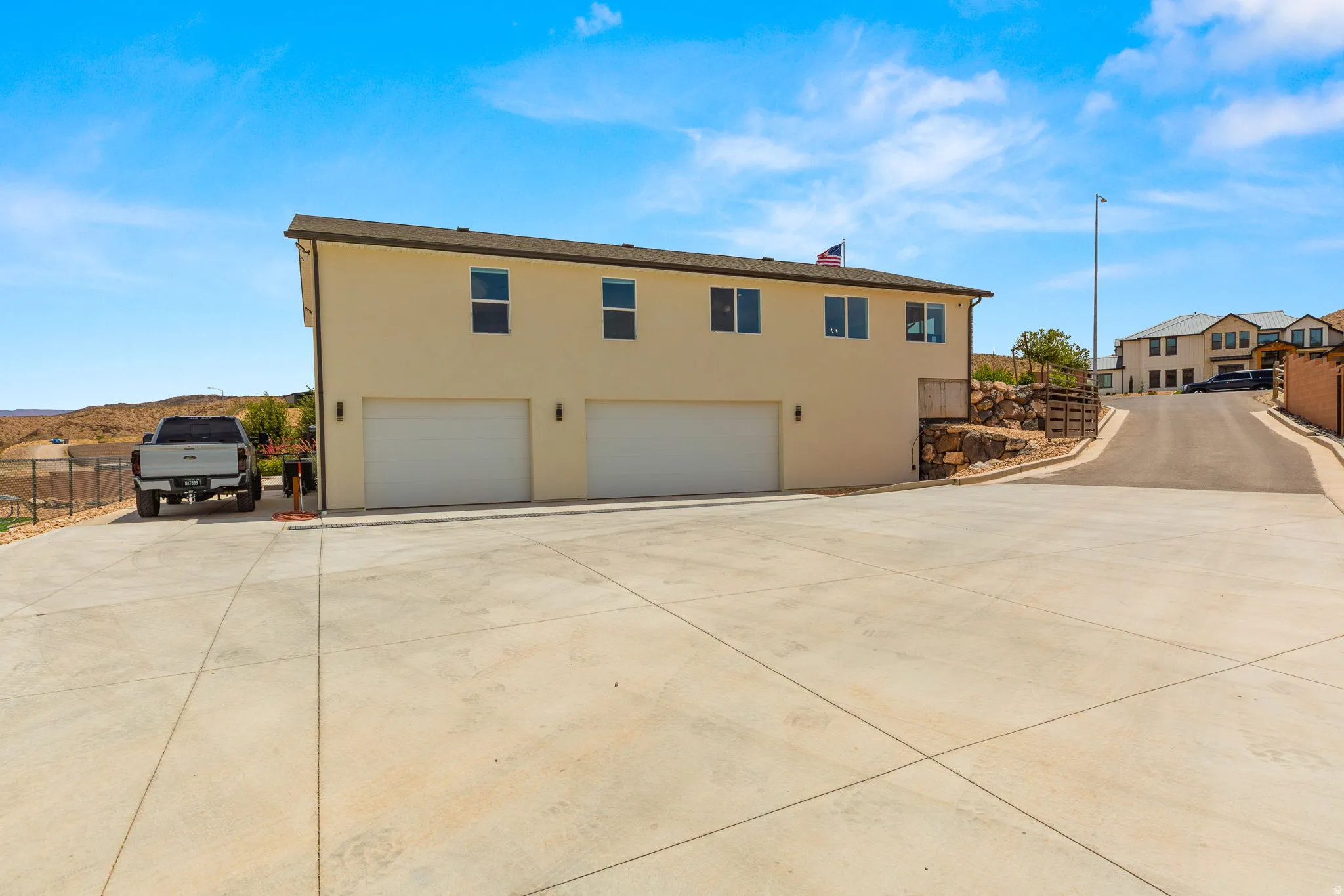 Two-story stucco property featuring a concrete driveway, two garage doors, and upper-level windows