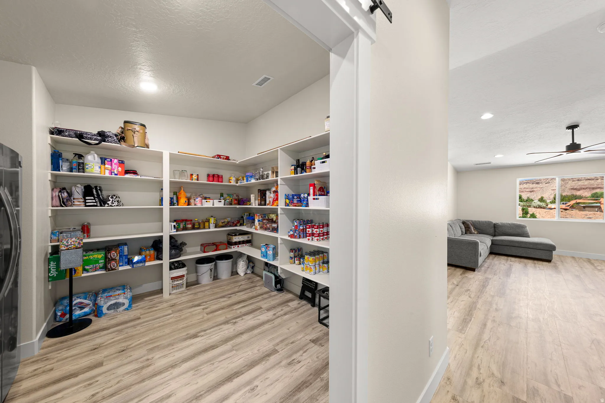 Spacious pantry featuring extensive built-in shelving, wood-finish flooring, and recessed lighting