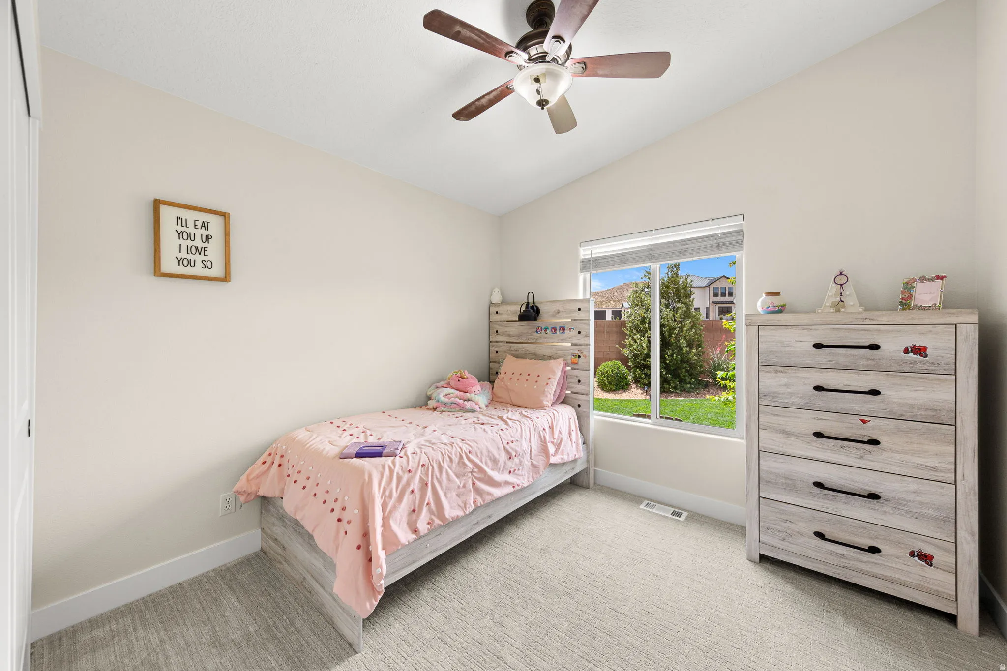 Interior room featuring an angled ceiling, a ceiling fan with wood-finish blades, and neutral-toned carpeting